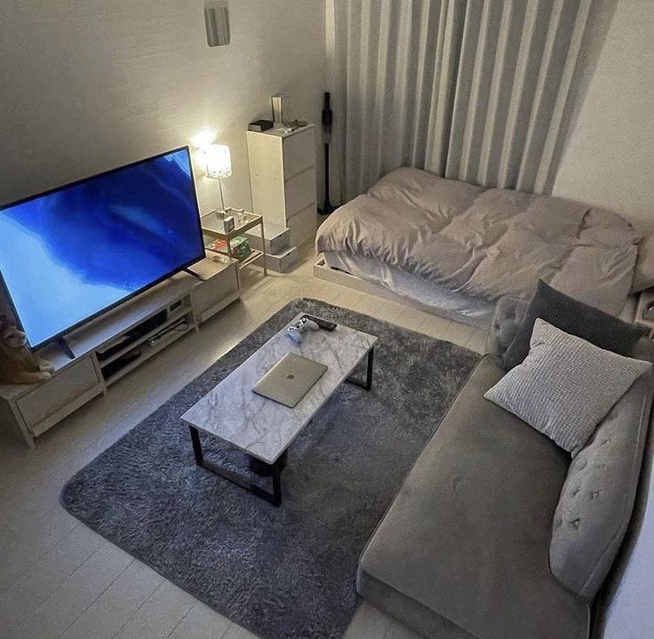 Ruang tamu minimalis dengan sofa abu-abu dan televisi