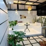 Teras rumah modern dengan tanaman dan meja makan di area semi outdoor