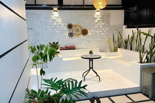 Teras rumah modern dengan tanaman dan meja makan di area semi outdoor